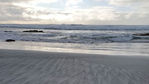 Una playa con dibujos en la arena y olas del océano.