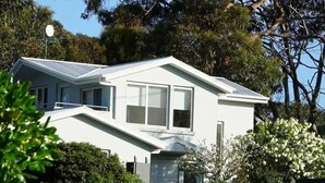 Una casa moderna de dos pisos con techo inclinado, ventanas grandes y un césped bien cuidado.