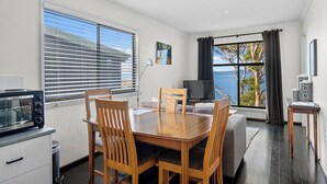 A modern kitchen with a microwave, wooden dining table, and chairs.