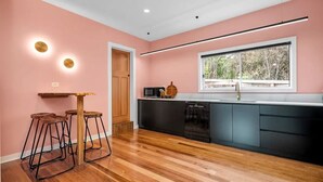 Una cucina moderna con pavimento in legno, un piano di lavoro nero e una finestra vista alberi.