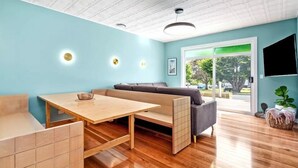 Un soggiorno moderno con un tavolo in legno, un divano e una TV a parete.