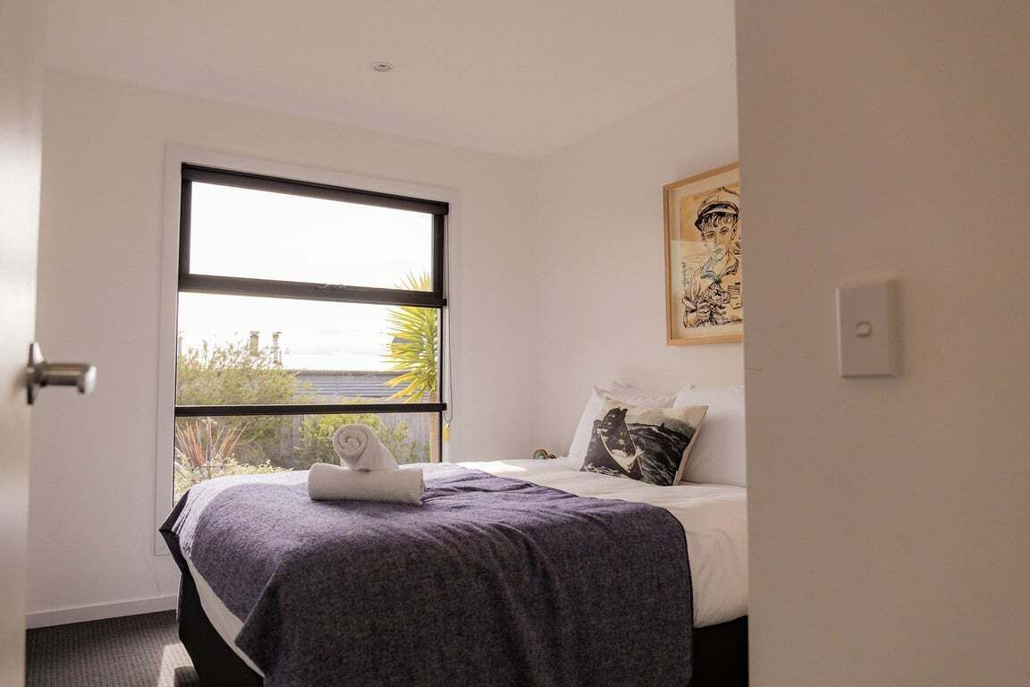 Ein Schlafzimmer mit Bett, Fenster und einem Bild an der Wand.