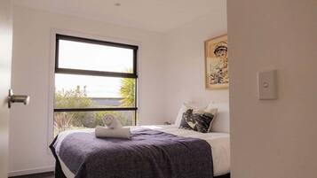 Ein Schlafzimmer mit Bett, Fenster und einem Bild an der Wand.