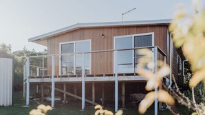 Una casa moderna de dos pisos con balcón, ventanas grandes y una antena visible.