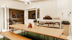 Una habitación acogedora con una mesa de madera, un banco y una estantería blanca con cestas.