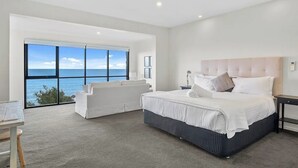 Un dormitorio moderno con una cama grande, un sofá y vistas al mar.