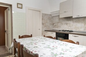 Una cocina con una mesa de comedor, sillas, armarios y una estufa.