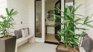 Een modern interieur met een bank, planten in potten en een deur naar een andere kamer.
