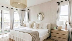 Een slaapkamer met een groot bed, een nachtkastje met een lamp, een kaptafel en een spiegel aan de muur.