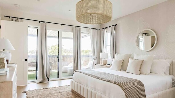 Een slaapkamer met een groot bed, een ronde spiegel en uitzicht op de omgeving via een schuifdeur.