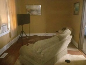 Cozy living space with a sofa, floor lamp, and small table, featuring a painting on the wall.