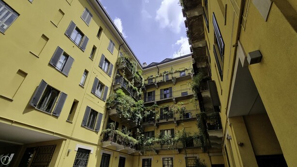 A narrow alleyway between yellow buildings with multiple balconies, some with plants. - Italianway Easy - Sarpi 10 B (Milan)