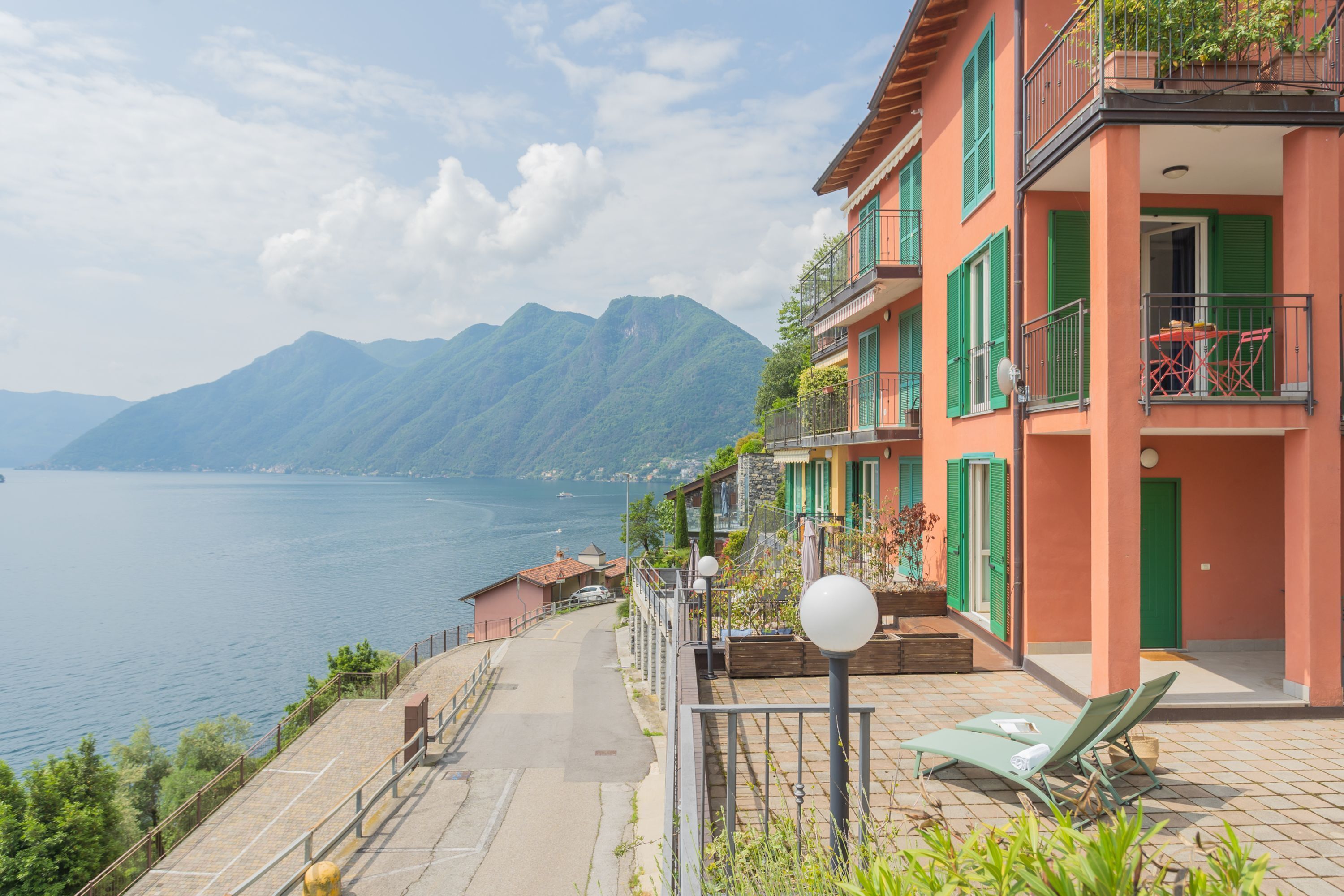 A coastal building with balconies overlooking a body of water and mountains.