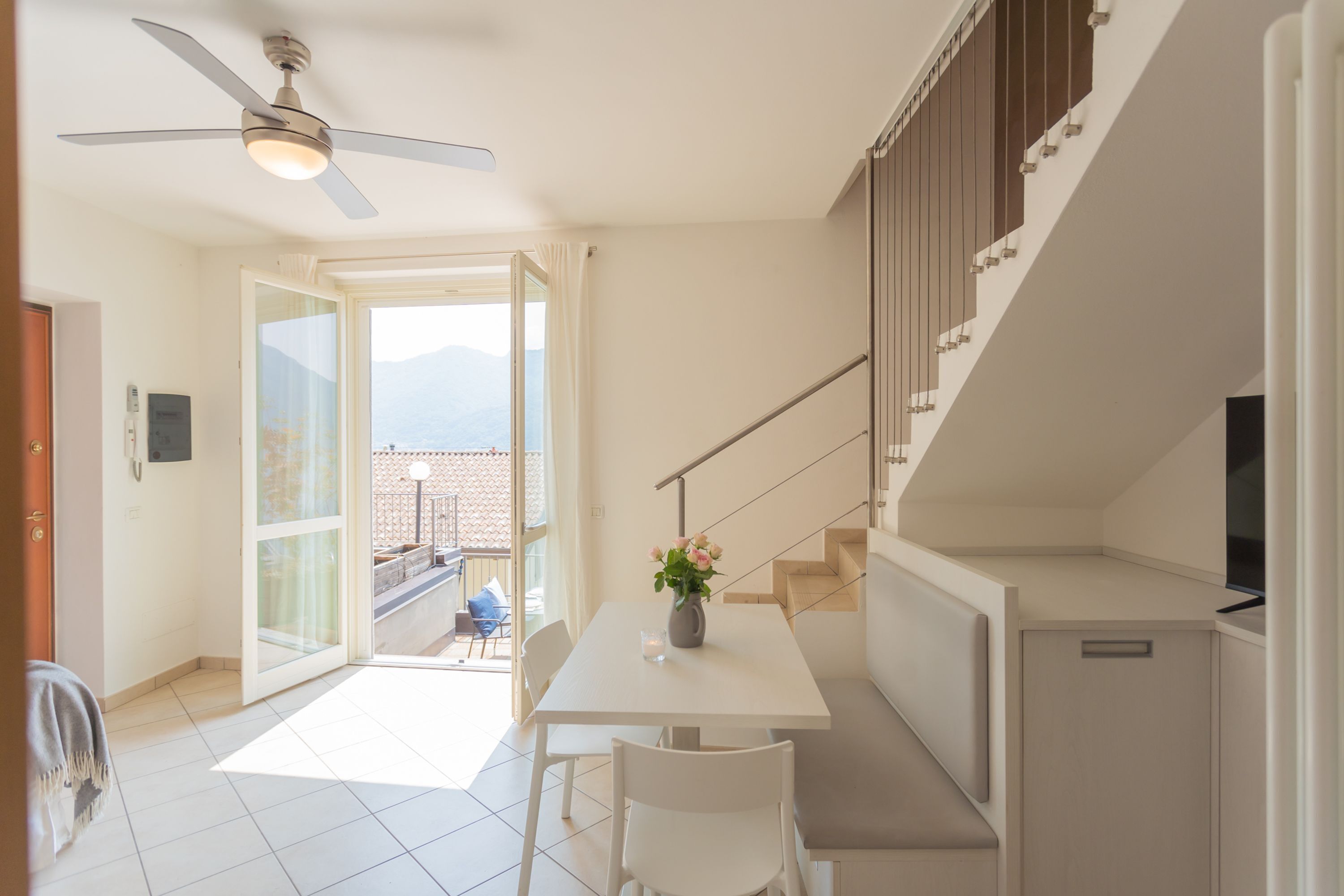 Una cocina moderna con comedor, ventilador de techo y vistas a través de la puerta de cristal.
