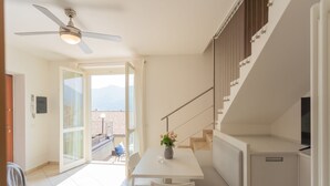 Une cuisine moderne avec un coin repas, un ventilateur de plafond et une vue à travers la porte vitrée.