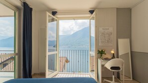 Une chambre à coucher comprenant un lit, un bureau, une chaise, une fenêtre avec des rideaux, un radiateur et un tableau encadré accroché au mur.