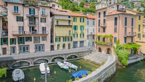 Un canal où sont amarrés des bateaux, bordé d’immeubles à plusieurs étages dotés de balcons et de boutiques.