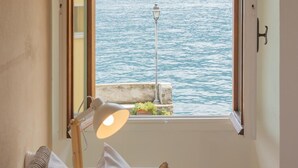 Une chambre avec une grande fenêtre donnant sur un plan d’eau et une lampe sur la table de chevet.