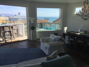 A spacious living area with a balcony overlooking the sea, a dining table with chairs, and a chandelier. - Beach House in the heart of Downtown Manhattan Beach! (Manhattan Beach)