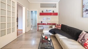 Una sala de estar con una mesa de centro de vidrio, un sofá y un mueble rojo.