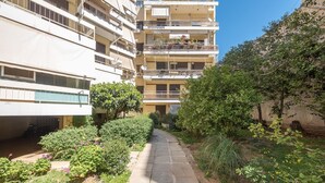 Un sendero estrecho bordeado por vegetación exuberante y un edificio residencial de varios pisos con balcones.