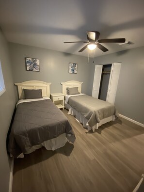 Ein Schlafzimmer mit zwei Betten, einem Deckenventilator und Bildern an den Wänden.