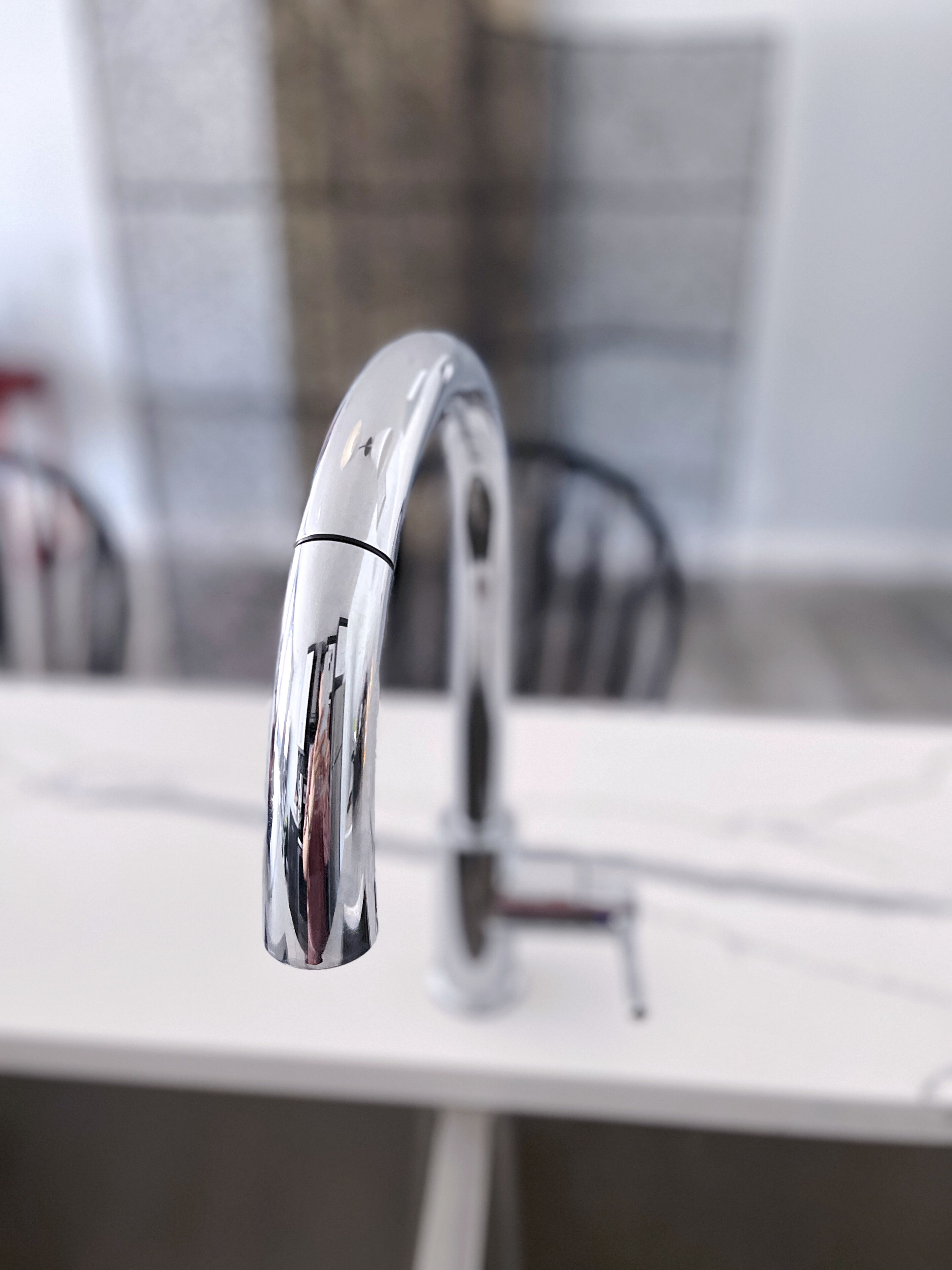 A modern kitchen with a sleek, chrome faucet mounted on a white countertop.