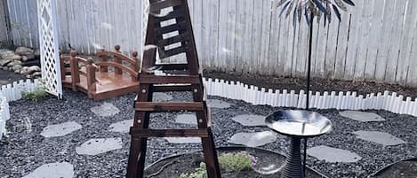A garden with a wooden ladder structure, a small table, and a decorative metal plant.