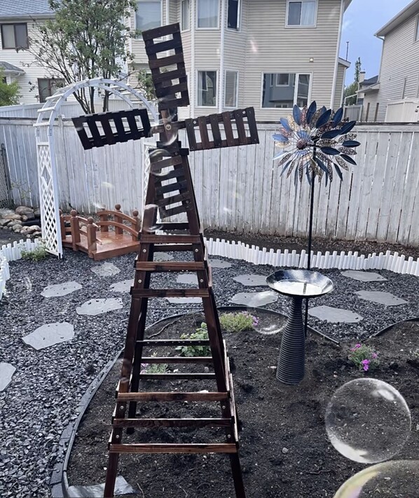 A garden with a wooden ladder structure, a small table, and a decorative metal plant. - Best garden private single room close LRT&free parking (Calgary)