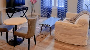 A living room with a flat-screen TV, a sofa, a coffee table, and a chair. - Best garden private single room close LRT&free parking (Calgary)