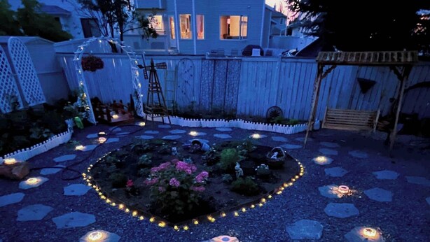 A garden with a central flower bed, surrounded by stepping stones and illuminated by ground lights. - Best garden private single room close LRT&free parking (Calgary)