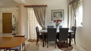 A dining area with a table and chairs, a vase with flowers, and a painting on the wall. - Paradeisos in Chalandri (Marousi)