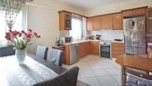 A kitchen with wooden cabinets, a stainless steel refrigerator, a microwave, and a dishwasher. - Paradeisos in Chalandri (Marousi)
