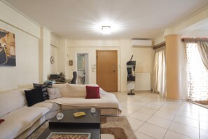 A living room with a sofa, coffee table, and a door leading to a bathroom. - Paradeisos in Chalandri (Marousi)