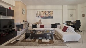 A modern living room with a sofa, coffee table, TV, fireplace, and artwork. - Paradeisos in Chalandri (Marousi)