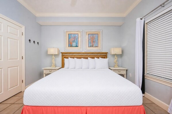 Una habitación de hotel con una cama grande, dos mesitas de noche, un cabecero de madera y dos obras de arte enmarcadas en la pared.
