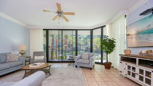 A living room with a sofa, armchair, coffee table, and TV stand. - Phoenix On The Bay 1122 3 Bedroom Condo (Orange Beach)