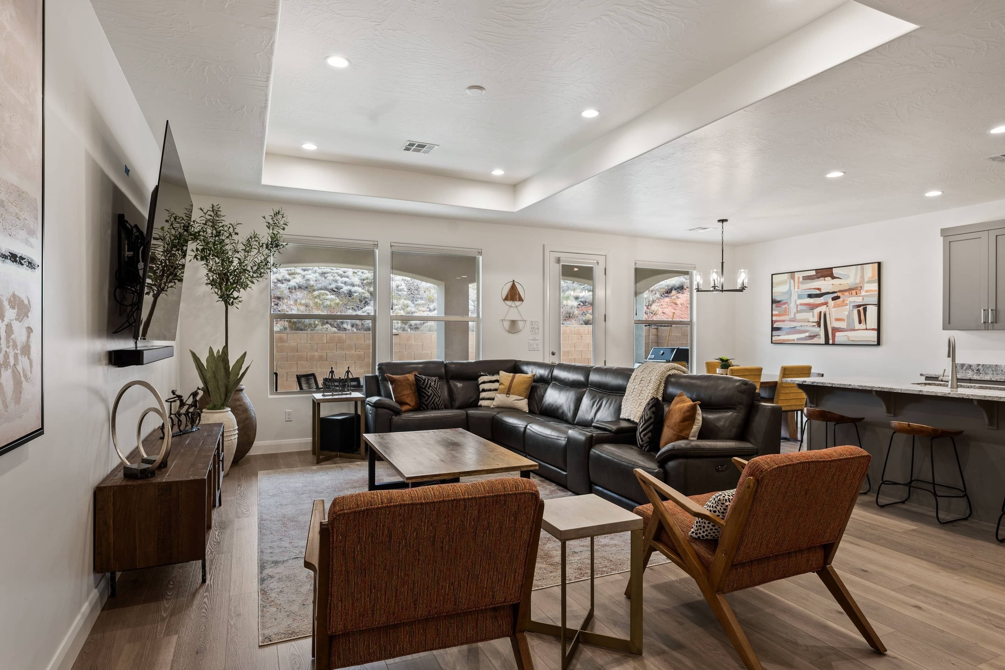 A modern living room with a leather sectional sofa, wooden coffee table, and two brown upholstered chairs.