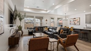 A modern living room with a leather sectional sofa, wooden coffee table, and two brown upholstered chairs.