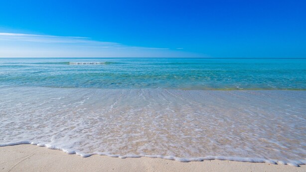 Ein Strand mit klarem, blauem Wasser und einem sandigen Ufer.