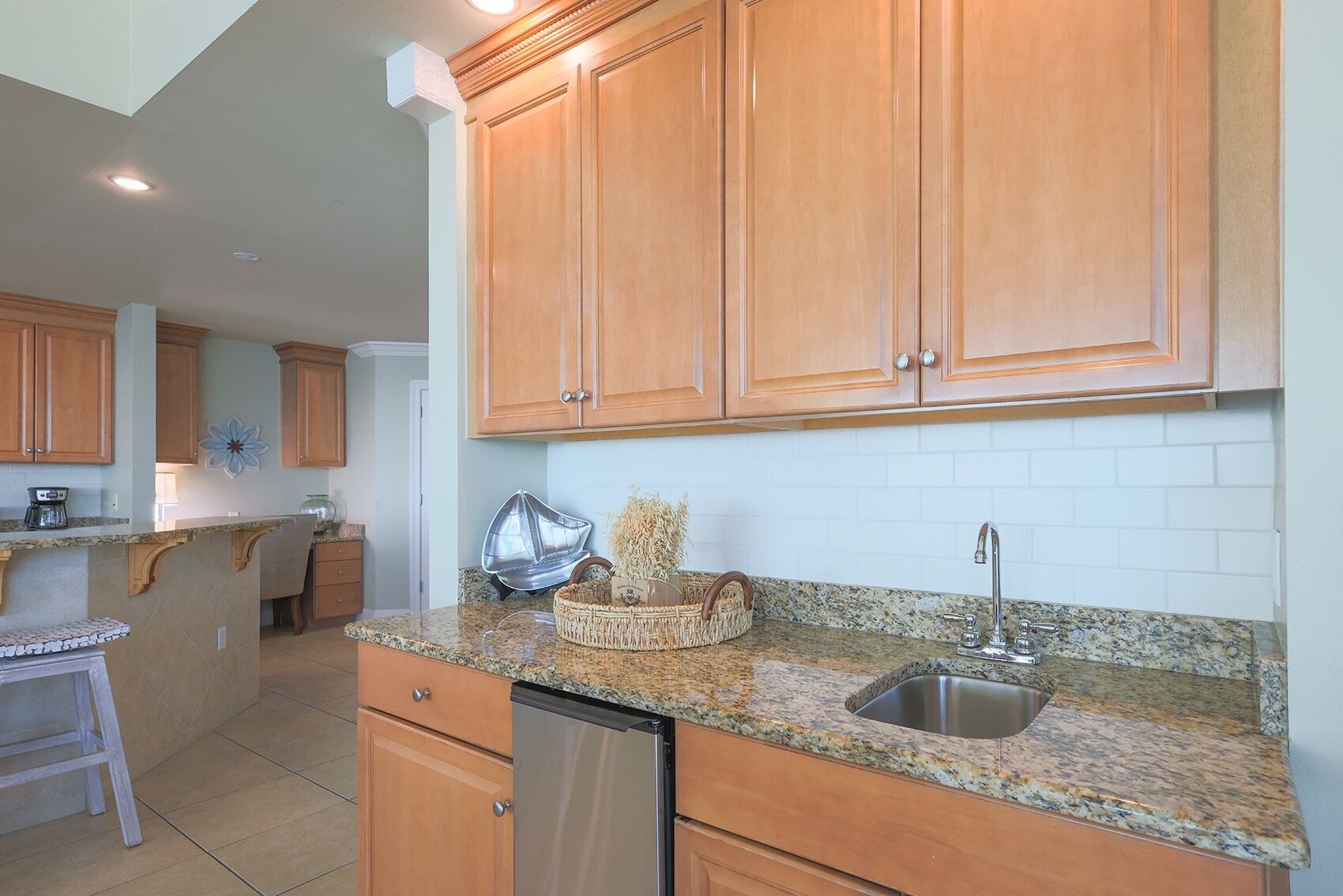 A kitchen with wooden cabinets, granite countertops, a stainless steel sink, and a dishwasher.