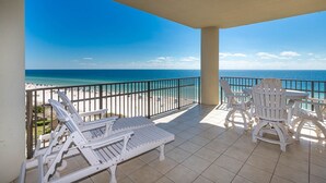 A balcony with white outdoor furniture, a view of the beach, and a clear blue sky. - Phoenix West 609 4 Bedroom Condo (Orange Beach)