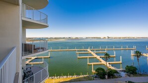 Un immeuble à plusieurs étages doté de balcons donnant sur une marina avec des quais et des bateaux.