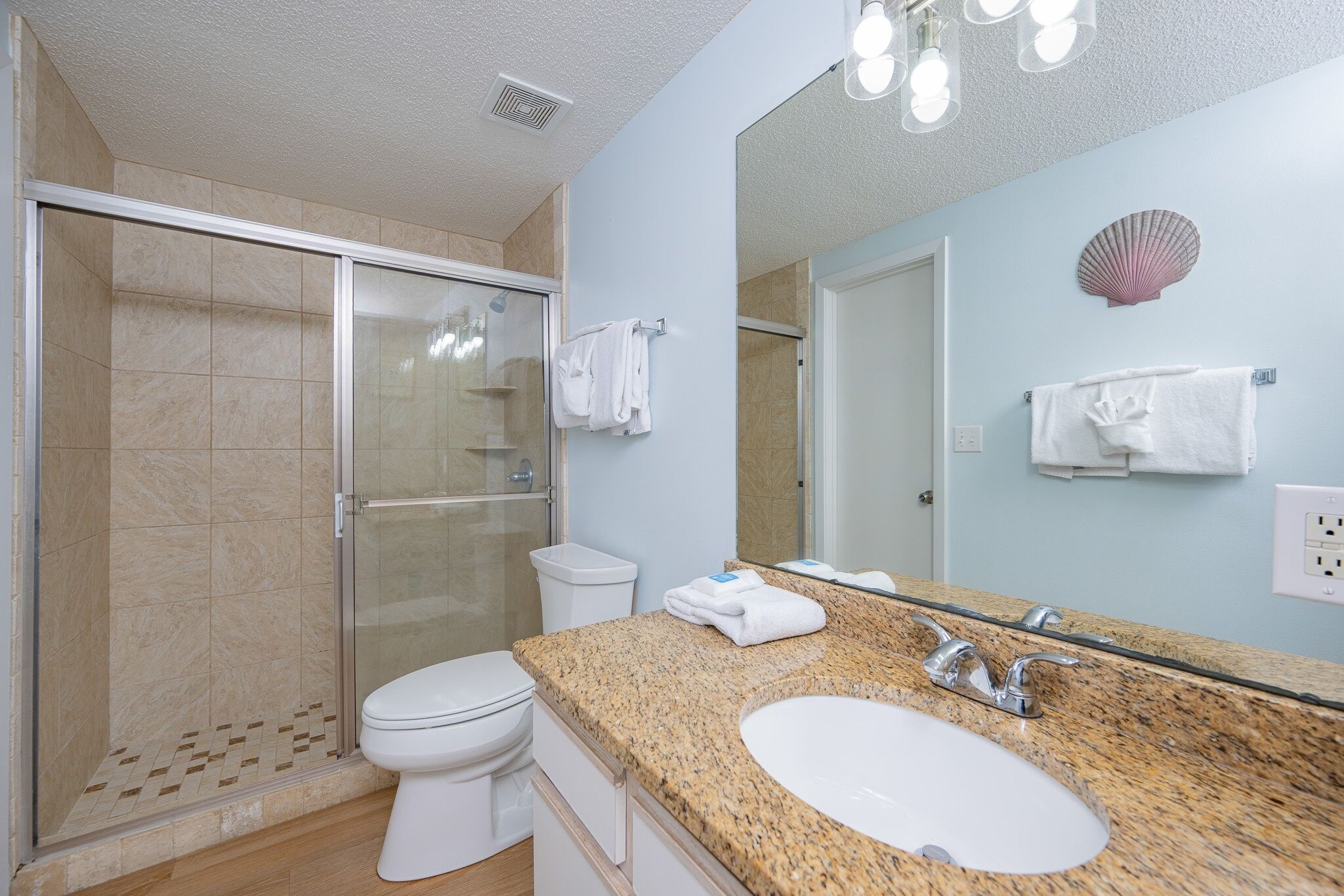 Een badkamer met douche, toilet, wastafel en een grote spiegel.