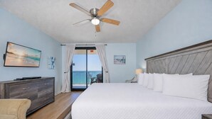 Une chambre d’hôtel avec un lit, un ventilateur de plafond, une télévision, une commode et une vue sur l’océan.