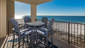 Un balcon avec une table et des chaises, donnant sur une plage.