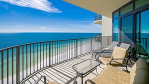 A balcony with a view of the ocean, furnished with chairs and a table.