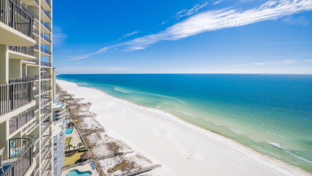 A beachfront hotel with balconies, a pool, and a view of the ocean.