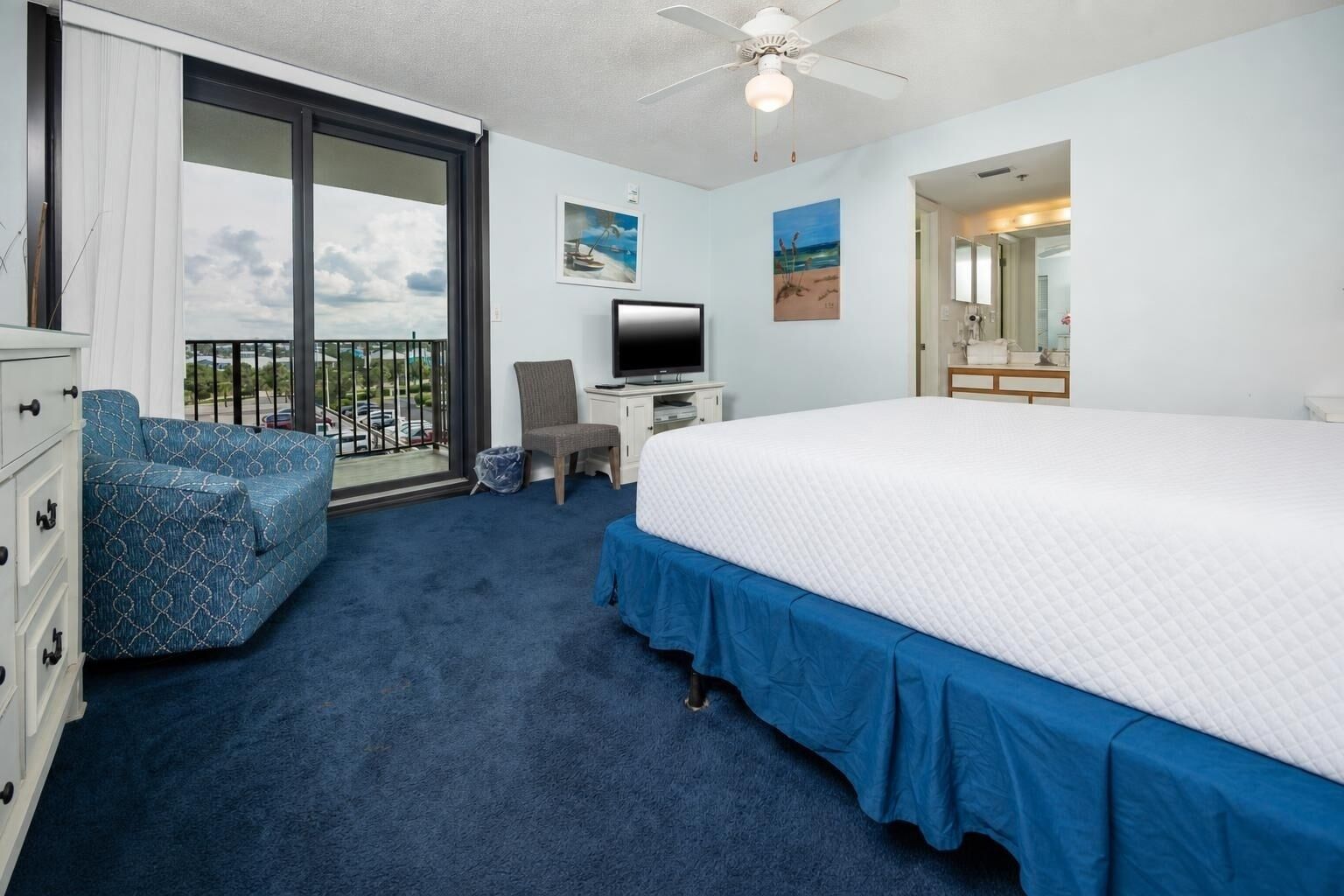 Een hotelkamer met een groot bed, een televisie, een stoel, een bureau en een balkon met uitzicht.