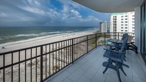 Un balcon avec vue sur la plage et l’océan, comprenant une table et des chaises.